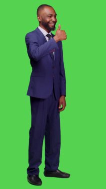 Dikey video: Yeni başlayanlar için gülümseyen işçilerin başparmak işareti göstermesi ve stüdyoda onay vermeleri, tüm vücudun yeşil ekranda görünmesi. Aşındırıcı yönetici kendinden emin ve pozitif hissediyor.