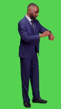 Dikey video: Kol saatine bakarak zamanı kontrol eden şirket çalışanlarının yan görüntüsü, tüm vücudun yeşil ekranda dakik olması. Ofis kıyafetli genç girişimci kontrol saati ve çalışma saati