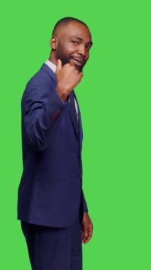 Dikey video: Takım elbiseli bir şirket yöneticisinin profili birini buraya çağırıyor, insanları yeşil ekran arkaplanı üzerinde ayakta durmaya çağırıyor. Genç adam iş adamı olarak çalışıyor ve kendine güveniyor.