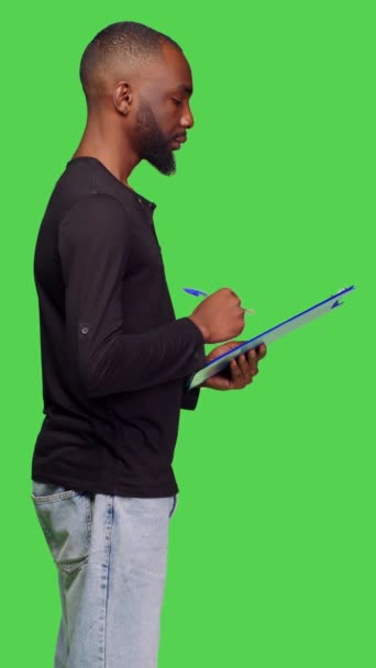 Vertical Video Profile Casual Person Taking Notes Papers Greenscreen Backdrop — Stock Video