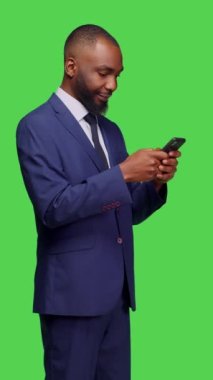 Dikey video: Afro-Amerikan bir adamın mesajlaşan mesajları tarayan uygulaması, sosyal medya sitesinde gezinen işletme müdürü. Ofis çalışanı elinde internet olan akıllı telefon tutuyor.