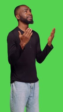 Dikey video: Afro-Amerikan bir adamın kamerada Tanrı 'ya dua edişinin yan görüntüsü, dua eden ellerin iyi şans dilemek için işaret ettiğini gösteriyor. Dini inancı olan genç bir yetişkin İsa 'dan af diliyor.