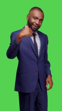 Dikey video: Takım elbiseli bir şirket yöneticisinin birini buraya çağırıp, insanları yeşil ekran arkaplanının üzerinde durmaya çağırması. Genç adam iş adamı olarak çalışıyor.