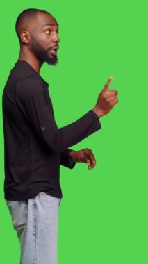 Dikey video: Afro-Amerikan bir adamın parmak izi yok, stüdyoda reddedilme ve inkar hareketi yapıyor. Genç erkek model yeşil ekran üzerinde onaylamadığını ve reddettiğini ifade ediyor.