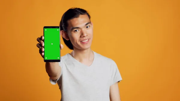 Wesoły Młody Facet Pokazuje Telefon Zielonym Ekranem Kamerze Patrząc Ekran — Zdjęcie stockowe