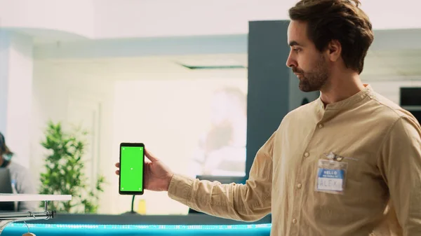 携帯電話に空白のコピースペーステンプレートを表示し 緑の画面でスマートフォンを保持男労働者 衣料品店で隔離されたクロマキーディスプレイを使用した白人市場アシスタント — ストック写真