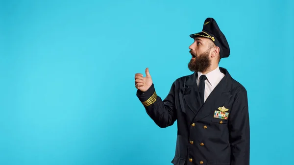カメラの左または右側を指している航空会社のパイロットは 横方向を示し 飛行業界で働いています 職業上の船長の格好をした若い男は別として — ストック写真