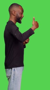 Dikey video: Kamerada, başarılı bir jest ve uzlaşma gösteren sıradan insanların profili. Genç adam yeşil ekranın arkasında onaylı sembol gibi duruyor.