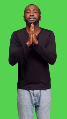 Dikey video: Stüdyoda Tanrı 'ya dua eden, şans ve şans dilemek için el ele tutuşan ruhani kişinin ön görüntüsü. Dini inancı olan genç bir adam Tanrı 'dan af diliyor.