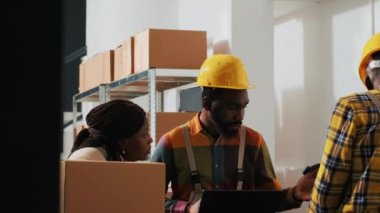 Afro-Amerikalı insanlar depolama odasında dizüstü bilgisayar siparişi vermeyi planlıyorlar. Ürün üretmeden önce perakende ürünlerle kutuları kontrol ediyorlar. Kalite kontrolü üzerinde çalışan çalışanlar.