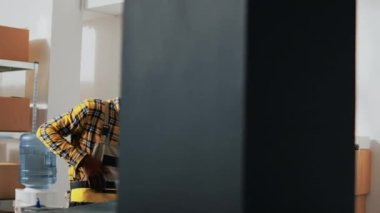 Afro-Amerikan işçiler kutularca ürüne bakıyorlar, ürün dağıtımı için perakende satış siparişi planlıyorlar. Depo çalışanları malzeme, lojistik ve envanteri kontrol ediyor. El kamerasıyla..