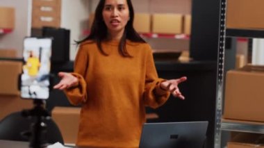 Depo çalışanı, reklam için sosyal medya yayın platformunu kullanarak telefonda pazarlama videosu çekiyor. Çevrimiçi reklam kampanyası için genç bayan çalışan ürün tanıtımını kaydediyor.