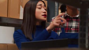 Ürünleri raflara dizen, karton kutuları raflara koyan ve envanteri kontrol eden insanlardan oluşan bir ekip. Kadın ve erkek sipariş sevkiyatını takip etmek için dizüstü bilgisayar kullanıyor. Küçük iş konsepti. El kamerasıyla..