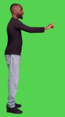 Dikey video: Kendine güvenen yetişkin profili birine el sallayarak kameraya bir şey düşürdüğünü söylüyor. Kot pantolonlu ve gömlekli genç iyimser bir adam.