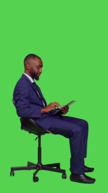 Dikey video: Afro-Amerikan bir adamın profili İnternet sitesinde geziniyor, online web sayfalarında dijital tablet ile ilgili iş bilgileri arıyor. Takım elbiseli genç işadamı,