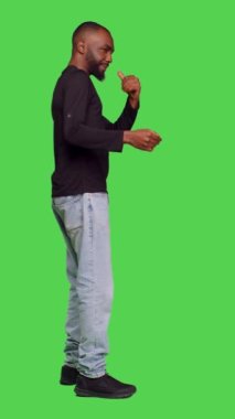 Dikey video: Kendine güvenen bir adamın sessiz işareti yapması ve stüdyoda mahremiyet göstermesi için birini çağırması. Delikanlı el kaldırarak sır saklamaya çalışıyor.