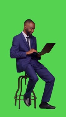 Dikey video: Şirketin internet sitesinde araştırma yapan, sandalyede oturan ve stüdyoda dizüstü bilgisayar kullanan çalışanlarının yan görüntüsü. Kablosuz bilgisayar üzerinde internet ağı sayfası ile çalışan yetişkin girişimci