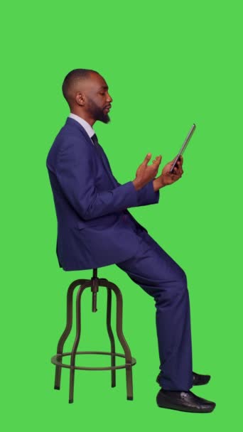 垂直视频 业务经理在网上交谈视频呼叫坐在工作室椅子上 全身绿色屏幕背景 青年创业者使用带有远程视频的平板电脑 — 图库视频影像