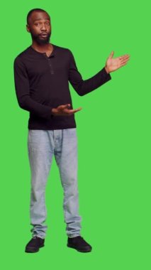 Dikey video: Afro-Amerikan bir adamın reklam için stüdyoda reklam oluşturması, reklam için sol ya da sağ tarafları göstermesi. Kot pantolon ve gömlek giymiş genç bir erkek model.