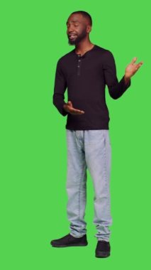 Dikey video: Afro-Amerikan bir adamın reklam için stüdyoda reklam oluşturması, reklam için sol ya da sağ tarafı göstermesi. Kot pantolon ve gömlek giymiş genç bir erkek model.