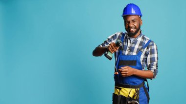 Duvarda matkap tabancası kullanan genç bir tamirci stüdyoda elektronik aletle çivi çakıyor. Miğferinde çivi tabancası olan inşaat mühendisi delme ve yenileme aletleri kullanıyor..