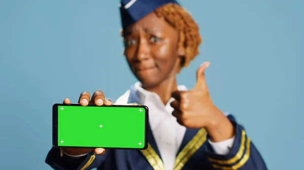 Flugbegleiterin Zeigt Auf Greenscreen Display Vor Blauem Hintergrund Der Kamera — Stockfoto