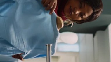 Dikey video: Kadın müşteri resmi veya günlük kıyafet alışverişi yapıyor, yeni moda mağazası ürünlerini kontrol ediyor. Delikanlı mağazada butik kıyafetleri kontrol ediyor, küçük işletme. El kamerasıyla..