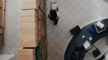 Afro-Amerikalı iş arkadaşları raflarda hisse senedi düzenliyor, perakende mağaza yönetimi için sipariş dağıtımı planlıyorlar. Kutularda ya da konteynırlarda çalışan genç çalışanlar. Drone görünümü.