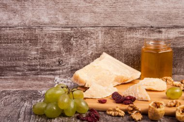Peynir, üzüm, fındık ve bal vintage ahşap arka plan stüdyo fotoğraf üzerinde