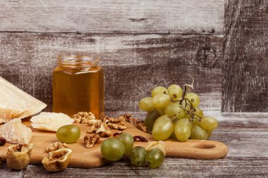 Parmesan, tatlım, fındık ve üzüm studio fotoğraf ahşap arka plan üzerinde. Sağlıklı yaşam tarzı