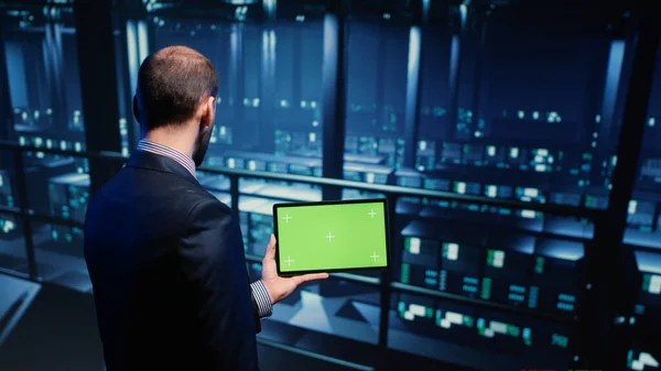 Support specialist using tablet with greenscreen display in modern data center, checking blank chroma key template. Database admin working with isolated mockup and hardware industry. Tripod shot.