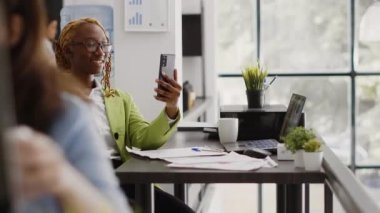 Şirket çalışanı cep telefonuyla video konferansı yapıyor, uzaktan görüntülü konferans sohbetinde insanlarla konuşuyor. İş yerinde internet üzerinden tele-iş yapan kadın işçi..