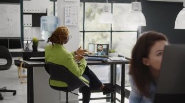Afrikalı Amerikalılar online video konferansında buluşuyorlar, uzaktan video konferans görüşmesini kullanarak müdürle araştırma hakkında konuşuyorlar. Masada oturan genç bir kadın telekonferansta adamla konuşuyor..