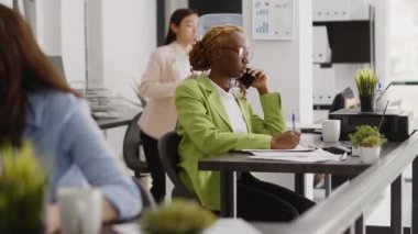 Afrika kökenli bir yetişkin, yatırım planı hakkında müdürle konuşmak için ofisteki telefon görüşmesini kullanıyor. Şirket çalışanı iş yerinde uzaktan konuşma yapıyor, telefon hattında sohbet ediyor..