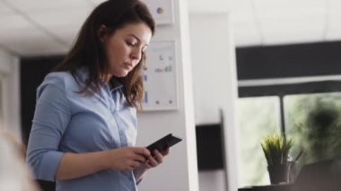 İşletme müdürü iş yerinde akıllı telefon uygulamasını kontrol ediyor, sosyal medyayı taramak için cep telefonu kullanıyor. Genç yetişkinler kâr ve kurumsal kalkınmayı artırmak için yatırım yapmayı planlıyorlar. El kamerasıyla..