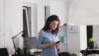 İdari asistan iş yerinde cep telefonu uygulamasını kontrol ediyor, sosyal medyayı taramak için akıllı telefon kullanıyor. Genç bir kadın kâr ve şirket gelişimini arttırmak için iş yatırımları planlıyor. El kamerasıyla..