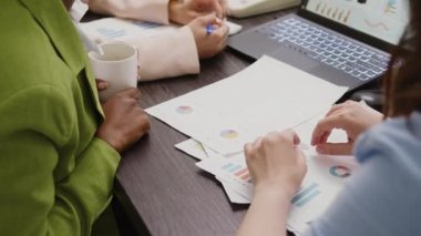 Çeşitli kadınlar belgelerle ilgili veri istatistiklerini analiz ediyor, toplantı salonunda yeni iş çözümleri bulmak için evraklara bakıyor. Bir grup çalışan pazarlama vizyonunu tartışıyor. Kapat..