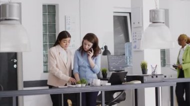 Masada yatırım planı üzerinde çalışan çeşitli insanlar, ofiste kalkınma için yeni bir strateji oluşturuyorlar. İş kadını iş yerinde iş arkadaşlarıyla cep telefonuyla konuşuyor..