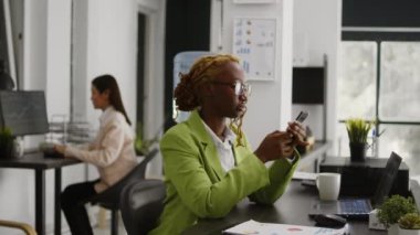 İş yerinde cep telefonu kullanan, masa başı iş planlama yatırımı yapan Afrikalı Amerikalı bir çalışan. Genç yönetici akıllı telefondan sosyal medya uygulamasını kontrol ediyor, kariyer geliştirme.