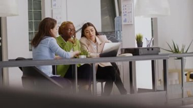Çeşitli iş arkadaşları toplantı brifinginde idari veri raporlarını göstererek kağıtlar ve bilgisayar ekranı istatistiklerini analiz ediyorlar. İnsanlar takım çalışması yaparak yeni geliştirme stratejilerini tartışıyor. El kamerasıyla..