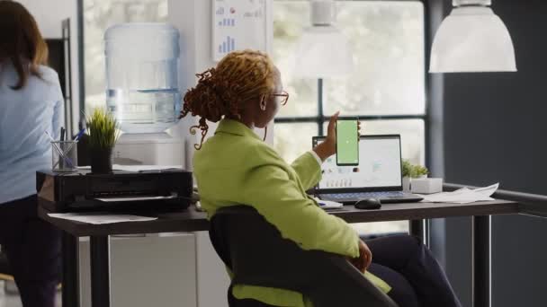 非洲裔美国妇女在电话中使用绿色屏幕 在创业办公室使用孤立的彩色键显示 公司员工检查智能手机屏幕上的空白模型模板 — 图库视频影像