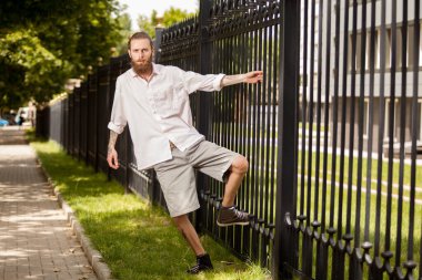 Şehir dışında bir çitin yanında poz sakallı hippi. Stil ve çeşitlilik