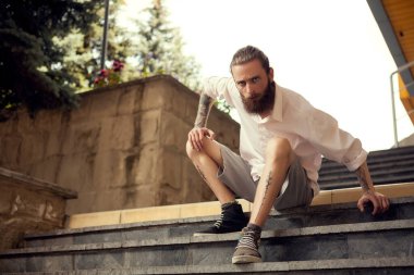 Beardead dövmeli serin sokak uzakta kameradan seyir merdivenlerde oturan adam arıyorum