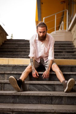 Dövmeli ve sakallı hippi şehirde poz veriyor.