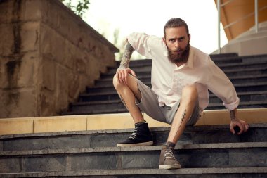 Beardead dövmeli serin sokak uzakta kameradan seyir merdivenlerde oturan adam arıyorum