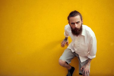 Moda stil üzerinde sarı duvarın dışında poz sakallı ve dövmeli adam. Moda ve stil