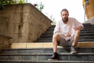 Güzel dövmeli ve sakallı adam şehirde poz veriyor.