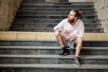 Dövmeli adam şehirde poz veriyor.