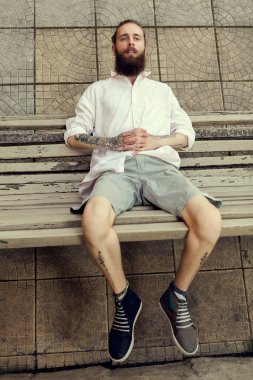 Tatoos ve sandalyede oturan ve moda stil içinde poz uzun sakal ile cool görünümlü adam. Nonconformism ve yenilikçi