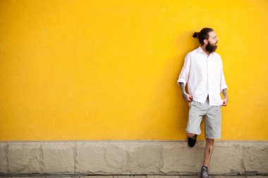 Sarı duvar açık poz üzerinde serin dövmeli sakallı hippi